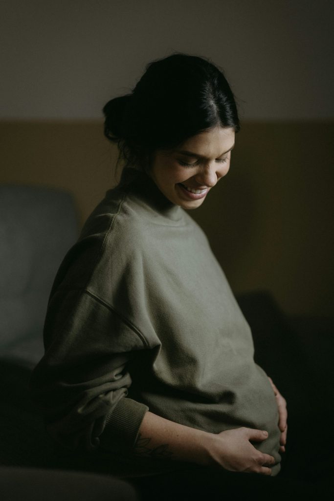 A pregnant woman sitting on a couch smiling